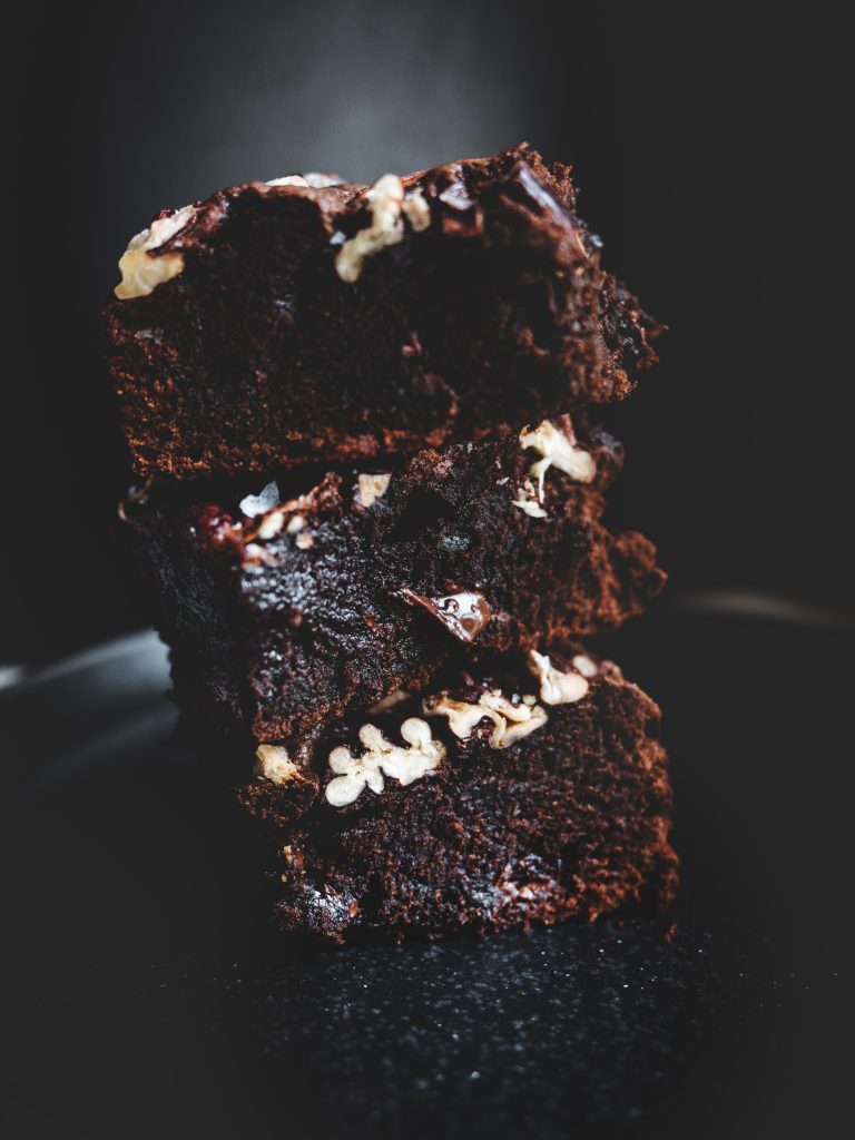Tre brownie al cioccolato con noci pecan impilati, interno morbido e fondente in evidenza.