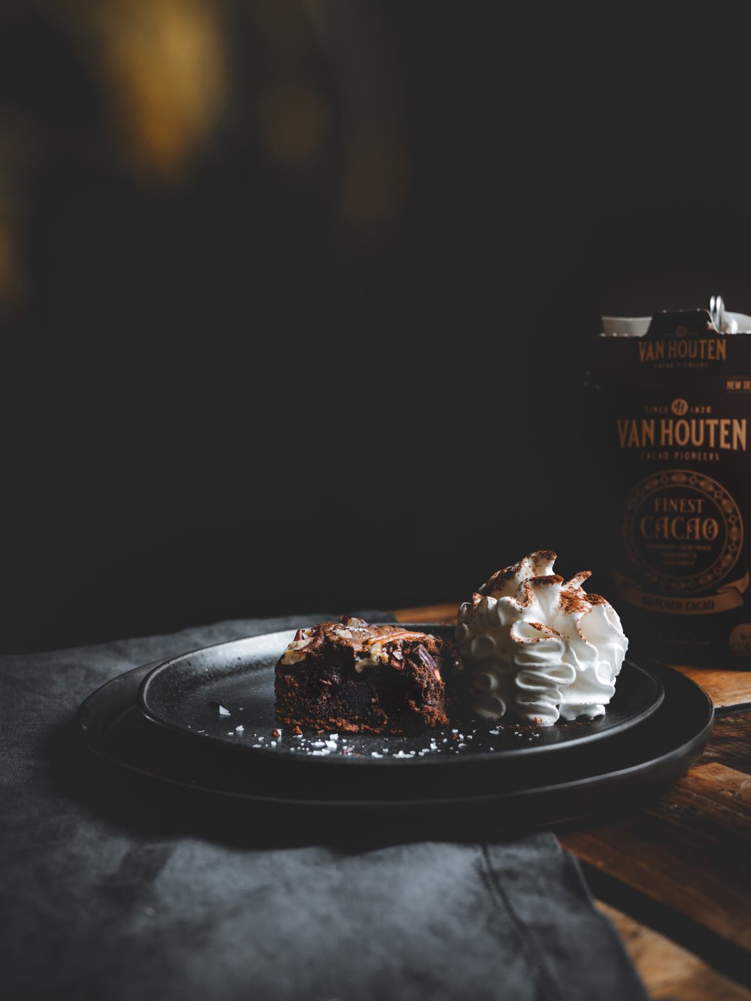 Brownie al cioccolato e caffè con noci pecan servito con panna montata e cacao.