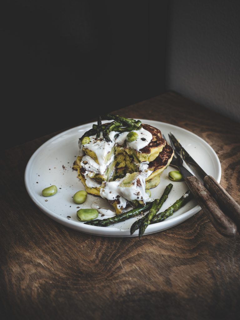 Dettaglio dell’interno morbido dei pancake salati con fave e asparagi tagliati a metà.
