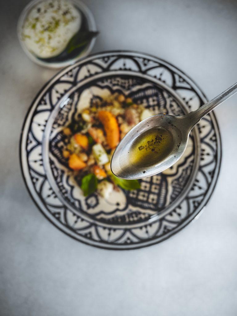 Cucchiaio con insalata di bulgur e quinoa, ceci, albicocche e barattiere