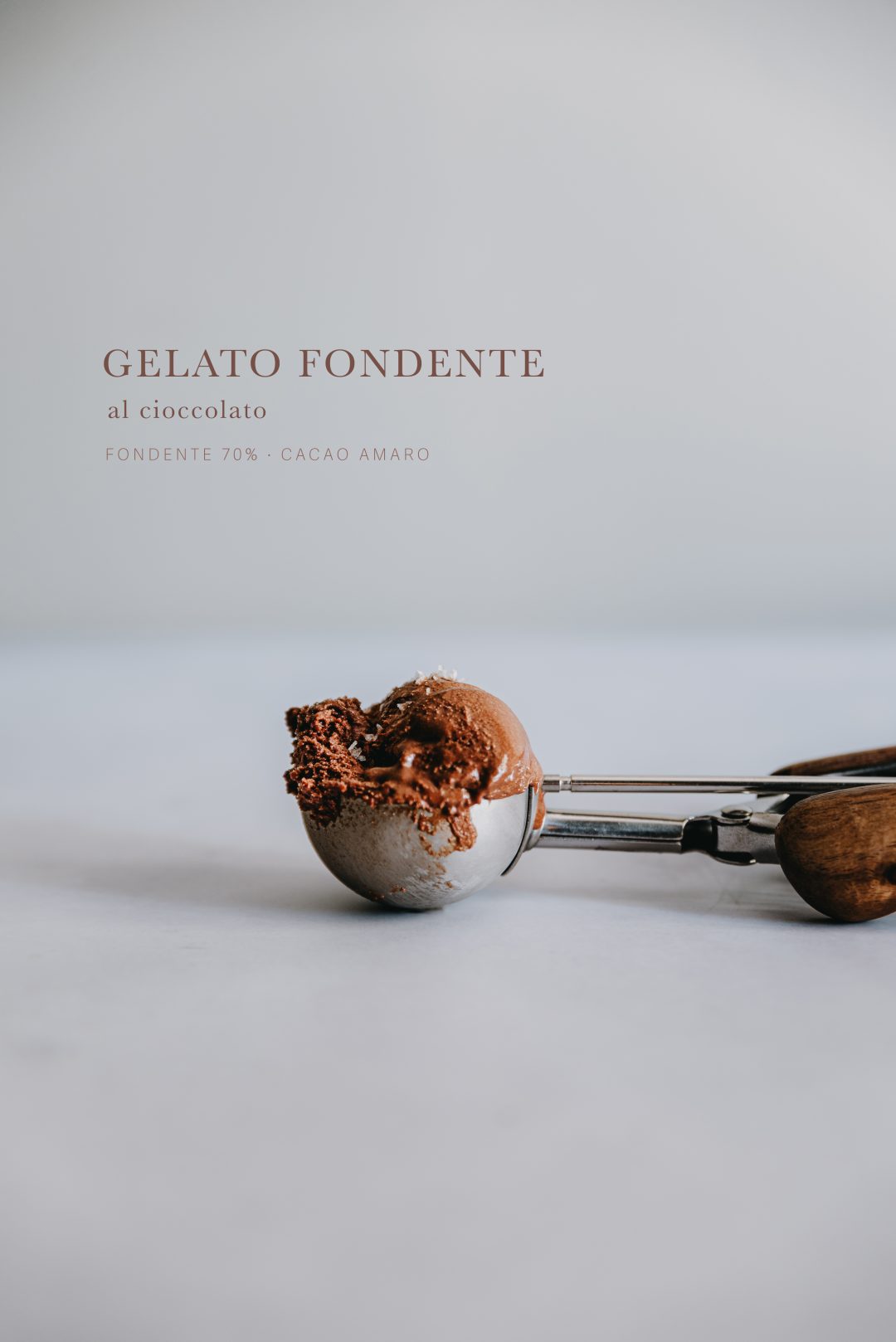 Gelato fondente al cioccolato servito su una paletta da gelato in acciaio con manico in legno.