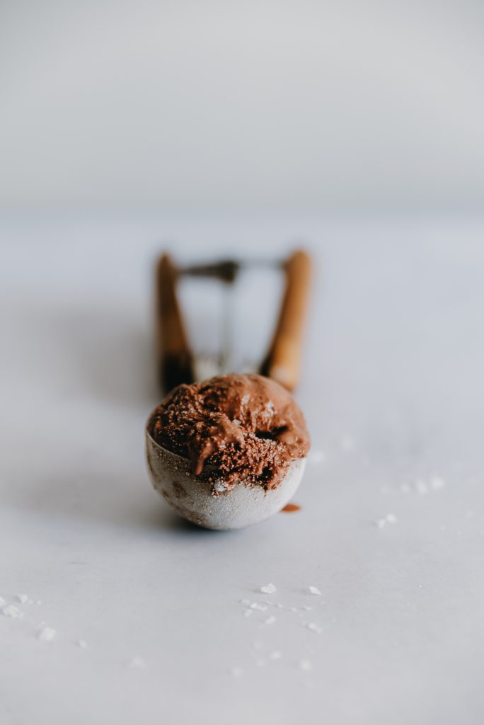 Primo piano di gelato fondente al cioccolato nella paletta, con consistenza cremosa e cristalli di sale in superficie