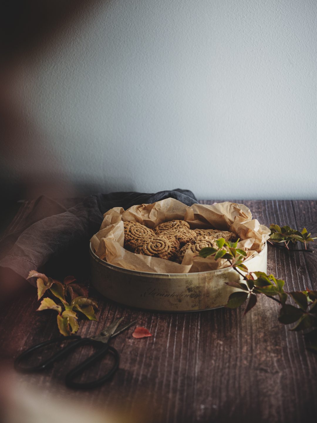 Biscotti rustici di farro, avena e frutta secca raccolti in una vecchia scatola di latta.